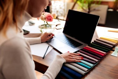 Bir iç mimar yeni bir proje üzerinde çalışıyor. Yeni mobilyalar için kumaş rengi paletinden renk seçiyorum. Meşe ağacından masa. Bir fincan kahve, vazodaki çiçekler mutlu müşterilerden. Yüksek kalite fotoğraf