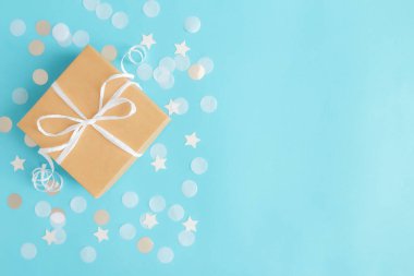 Kurdele, yıldız ve daire şeklinde kağıt konfeti ya da mavi pastel arka planda parlayan simlerle izole edilmiş el işi kağıt hediye kutusuyla yatıyordu. Yüksek kalite fotoğraf