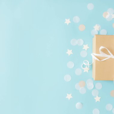 Kurdele, yıldız ve daire şeklinde kağıt konfeti ya da mavi pastel arka planda parlayan simlerle izole edilmiş el işi kağıt hediye kutusuyla yatıyordu. Yüksek kalite fotoğraf