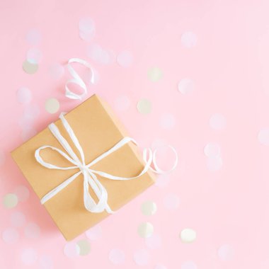 Kurdele, yıldız ve daire şeklinde kağıt konfeti ya da pembe pastel arka planda parlayan simlerle izole edilmiş el işi kağıt hediye kutusuyla yatıyordu. Yüksek kalite fotoğraf