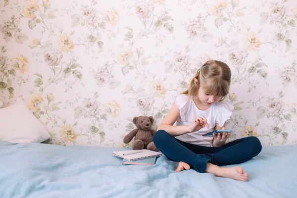 Маленька Дівчинка Сидить Ліжку Стильній Спальні Тримає Телефон Читає Щось — стокове фото