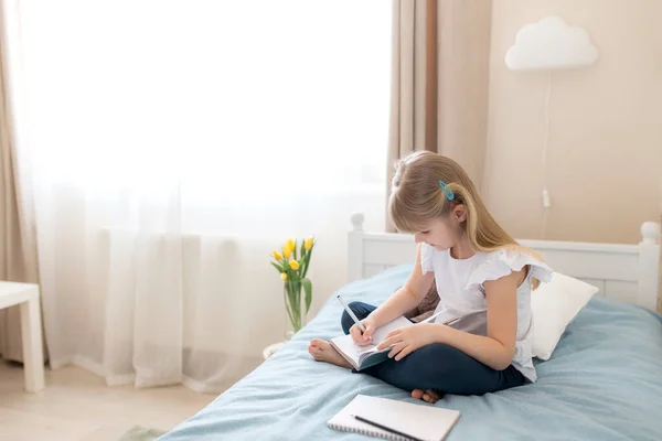Маленька Дівчинка Сидить Ліжку Спальні Пише Блакитній Книзі Концепція Освіти — стокове фото