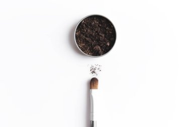 Kapta koyu kahverengi yüz gölgesi ve göz farı ya da makyaj fırçası. Makyaj konsepti beyaz arkaplanda yatıyordu