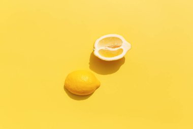 Sarı arka planda gölgesi olan iki dilim limon. Sağlıklı beslenme, seyahat veya tatil kavramı