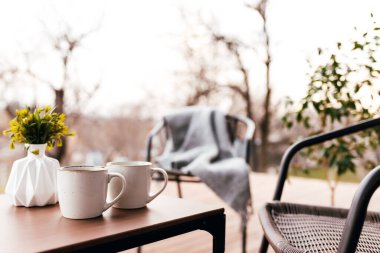 Akşam günbatımında, ahşap kahverengi terasın üzerindeki masada iki fincan kahve. Rahatlama, aşıklar romantik akşam konsepti