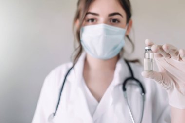 Doktor ya da hemşire elinde cam şişe antivirüs aşısı tutuyor.