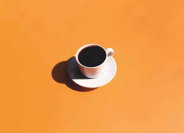 Tasse und Teller Kaffee mit Sonnenschatten auf gelbem Terrakottahintergrund — Stockfoto