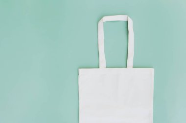 Çevre beyazı kağıt çanta yeşil arka planda, fotokopi alanı boş reklam alanında duruyordu. Paketleme şablonu maketi. Teslimat hizmeti, yeniden kullanılabilir ve geri dönüştürülebilir kaynak kavramı