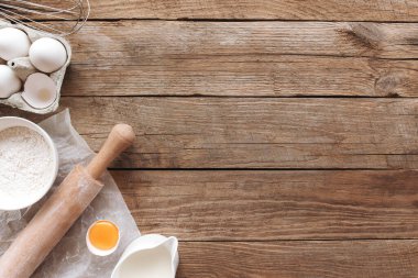 Pişirme malzemeleri, eski ahşap arka planda mutfak aletleri. Hamur pişirme, yumurta sarısı, un, merdane, süt, parşömen kağıdı çırpma, tuz, sodyum. Fotokopi alanı olan düz konsept fotoğraf
