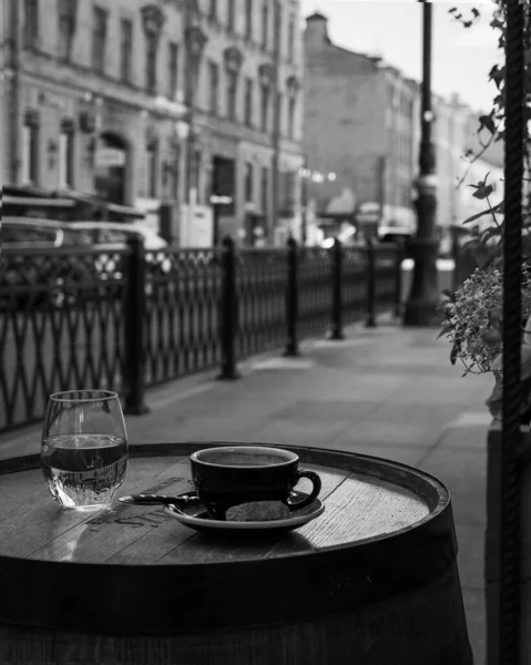 Ön planda, masanın üzerinde, bir fincan kahve ve bir bardak su var.