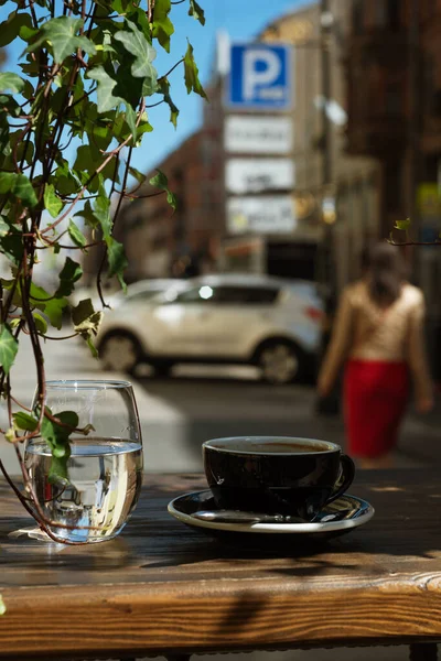 Ön planda bir fincan kahve ve bir bardak su var.