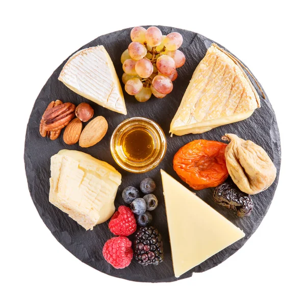 Cheese plate. French cheese with nuts, grape, berries, dried fruits and honey on slate board isolated on white. Camembert, Livarote, Pont-L'eveque cheese from Normandy and comte cheese. Top view.