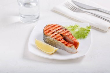 Limonlu ızgara kırmızı somon bifteği ve beyaz tabakta marul. Somon balığı, somon balığı veya Oncorhynchus nerka.