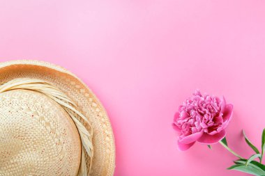 Pembe arka planda güzel pembe şakayık ve hasır şapka. Düz konum, üst görünüm, kopyalama alanı.