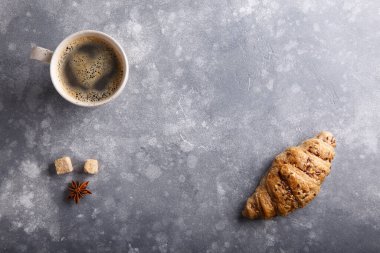 Bir fincan kahve ve gri arka planda taze pişmiş kruvasan. Üst Manzara. Boşluğu kopyala.