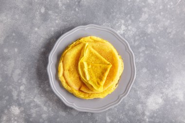 Gri tabakta sarı krep. Beton arka planda zerdeçal boyalı krep yığını. Üst görünüm, alanı kopyala.