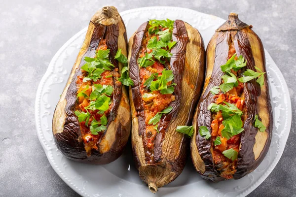 Whole eggplant stuffed with vegetables on white plate on grey background . Imam bayildi, Turkish cuisine