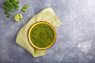 Domatesli salsa verde. Gri masada bir kase baharatlı yeşil sos, Meksika mutfağı. Üst Manzara. Boşluğu kopyala.