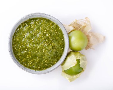 Domatesli salsa verde. Beyaz masada bir kase baharatlı yeşil sos, Meksika mutfağı. Üst görünüm.