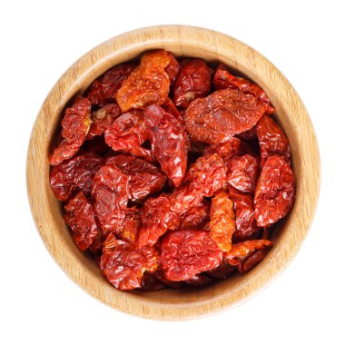 Kırmızı güneş, ahşap kasede tuz bulunan kurutulmuş domatesler beyazın üzerinde izole edilmiş. Üst görünüm.