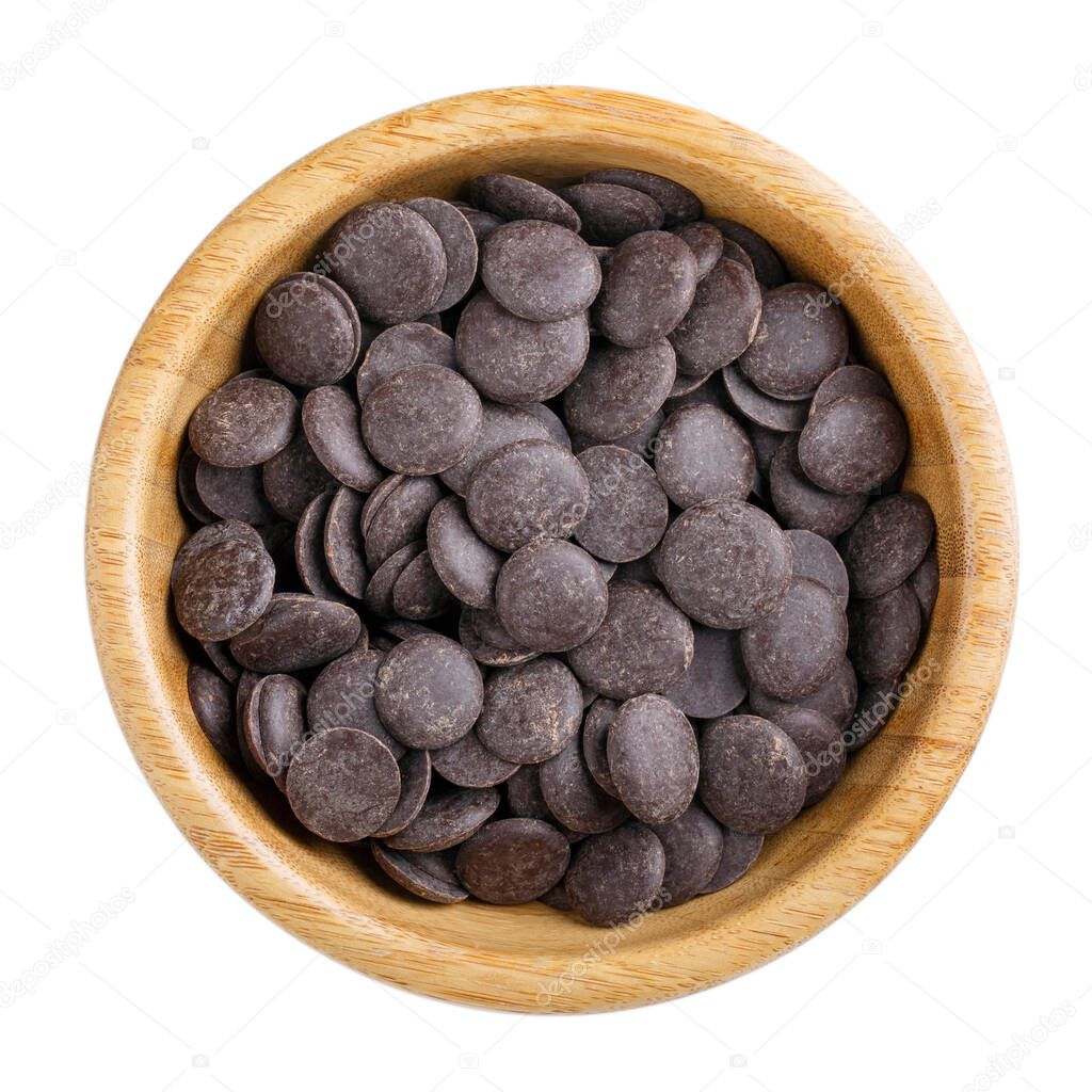 Dark unsweetened chocolate chips in wooden bowl isolated on white. Top view.