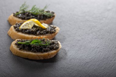 Siyah arkaplanda siyah havyarlı sandviçler. Yakın plan, kopyalama alanı.