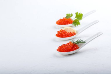 Beyaz arka planda seramik kaşıklarda kırmızı havyar. Yakın plan, kopyalama alanı.