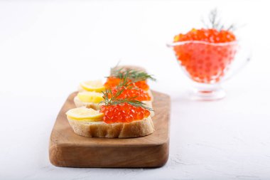 Kırmızı havyarlı sandviçler beyaz arka planda tahta kesme tahtasının üzerinde servis ediliyor. Yakın plan, kopyalama alanı.