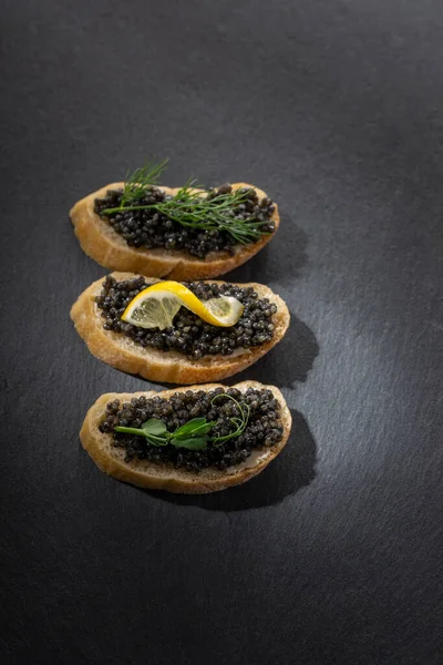 Siyah arkaplanda siyah havyarlı sandviçler. Yakın plan, kopyalama alanı.