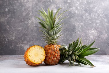 Gri arka planda tam ve dilimlenmiş ananas. Boşluğu kopyala.