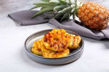 Beton arka planda gri tabakta ızgara ananas dilimleri..