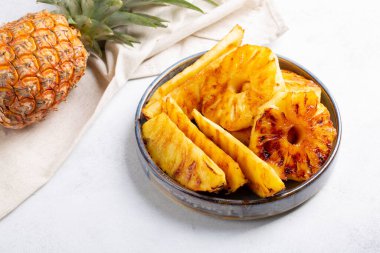 Beton arka planda gri tabakta ızgara ananas dilimleri..