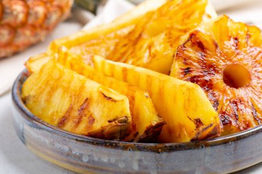 Beton arka planda gri tabakta ızgara ananas dilimleri..