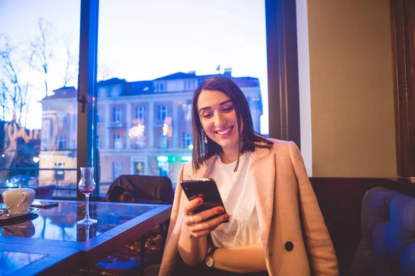 Beautiful young woman in restaurant happy when using phone and social networks