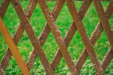 Arka planda yeşil çimenler olan eski ahşap çitler.