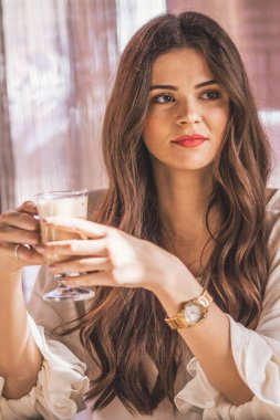 Kafede bir fincan kahveyle gülümseyen kadın