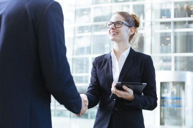 Two young business people shaking hands clipart