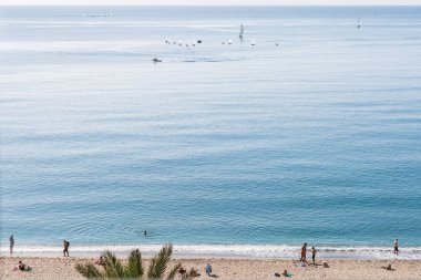 Kasım ayında güneşli bir günde Almerya, Güney İspanya 'da bazı insanlar ve yelkenlilerle plaj manzarası.