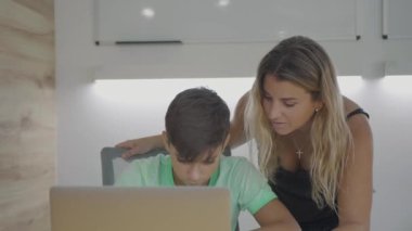 Anne ve oğul evde ev ödevi ve uzaktan eğitim için dizüstü bilgisayar kullanıyor. Çünkü koronavirüs ve sınıf e-öğrenim platformunda.