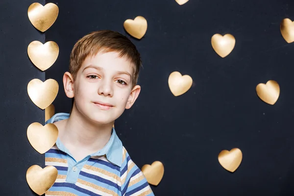 Uśmiechnięty chłopiec zerkając na tle Złotego serca — Zdjęcie stockowe