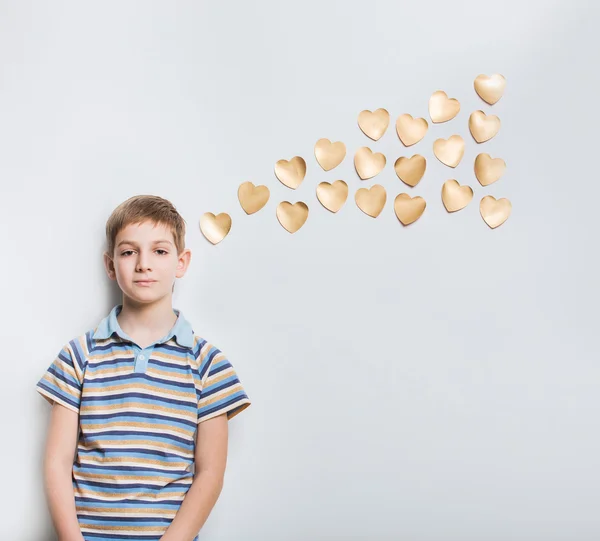 Altın kalpler ile ışık gri arka plan üzerinde düşünme çocuk — Stok fotoğraf