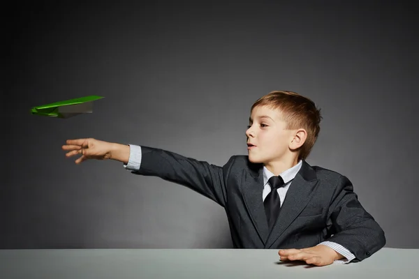 Ragazzo in giacca e cravatta lancio aereo carta verde — Foto Stock