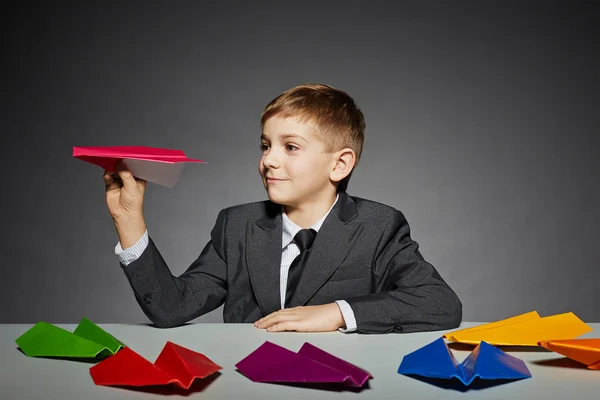 Menino de terno lançando avião de papel colorido — Fotografia de Stock