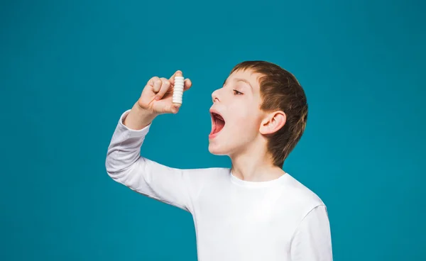 Niño en ropa blanca tratar de comer un montón de pastillas —  Fotos de Stock