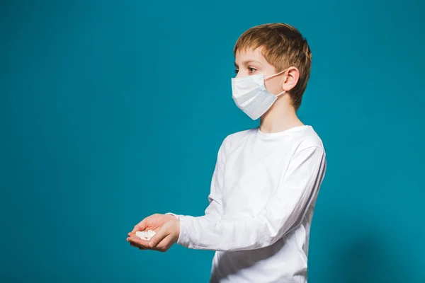 Junge mit weißer Schutzmaske hält Pillen in der Hand — Stockfoto