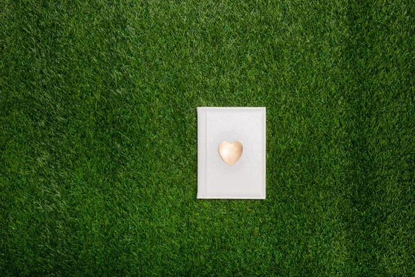 White book with gold heart lying on the grass — Stock Photo, Image