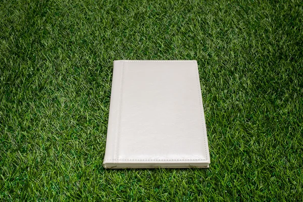 White leather book lying on the green grass