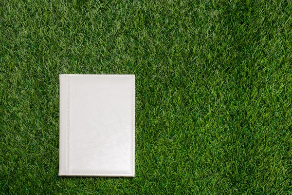 White leather empty book lying on the grass — Stock Photo, Image