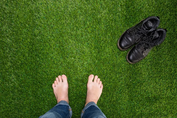 Mens feet resting on green grass with standing boots — Stock Photo, Image