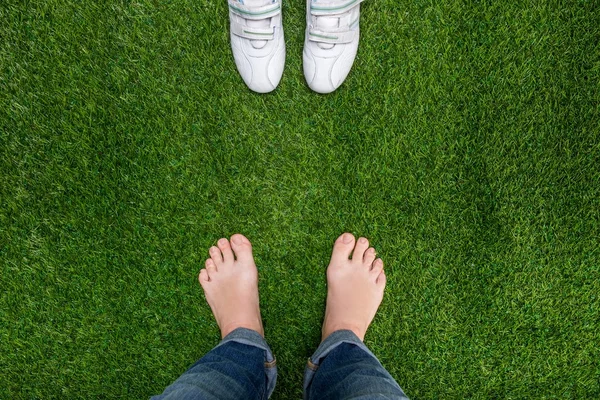 Voeten rust op gras met sneakers permanent tegenovergestelde — Stockfoto